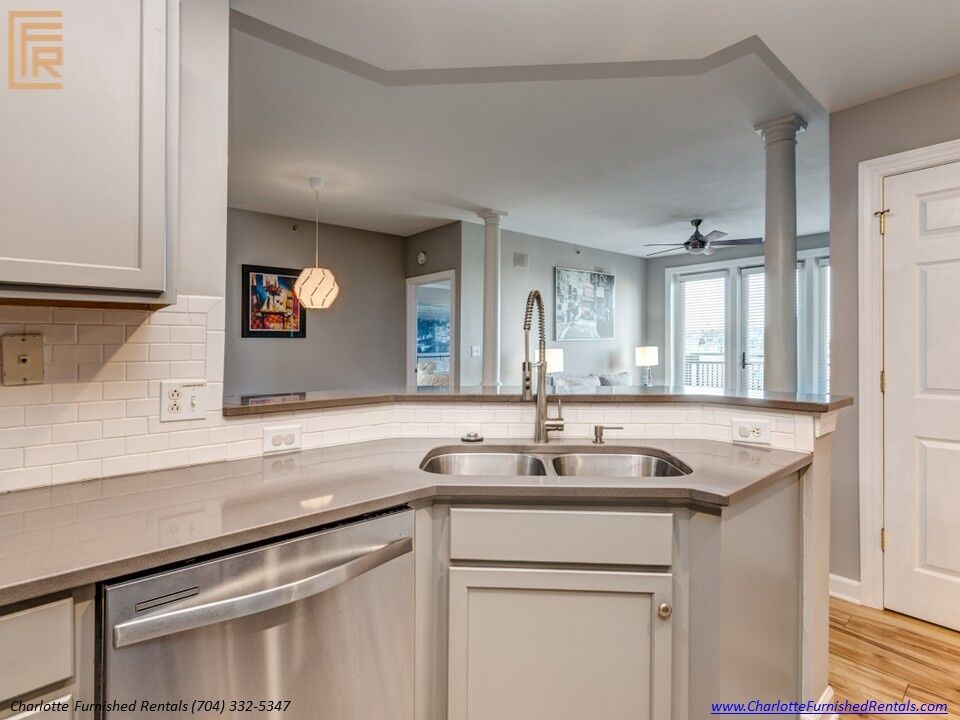 718-west-trade-unit-813-kitchen-breakfast-bar-opening-to-living-room-uptown-charlotte Updated kitchen with stainless appliances at 718 West Trade Street Unit 813, a furnished rental in Uptown Charlotte