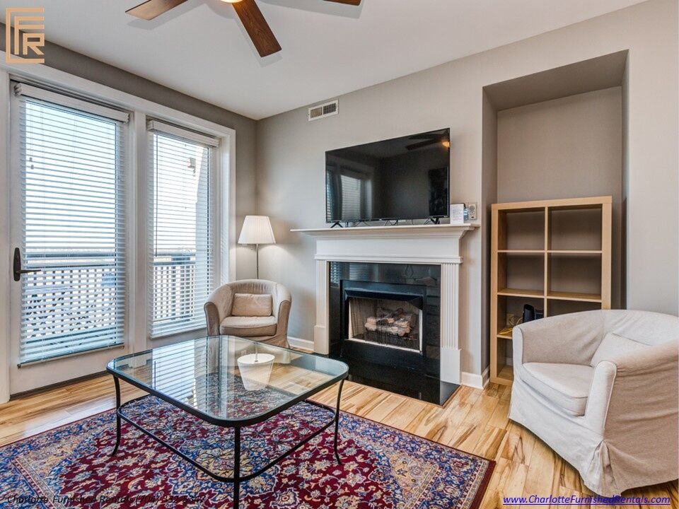 718-west-trade-unit-813-living-room-fireplace-and-balcony-doors-uptown-charlotte Living room fireplace and balcony doors at 718 West Trade Street Unit 813, a furnished rental in Uptown Charlotte