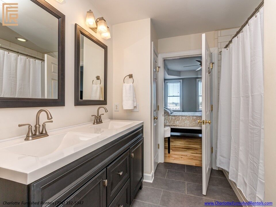 718-west-trade-unit-813-primary-bathroom-dual-vanity-and-tub-shower-uptown-charlotte Primary bathroom dual vanity and tub shower at 718 West Trade Street Unit 813, a furnished rental in Uptown Charlotte