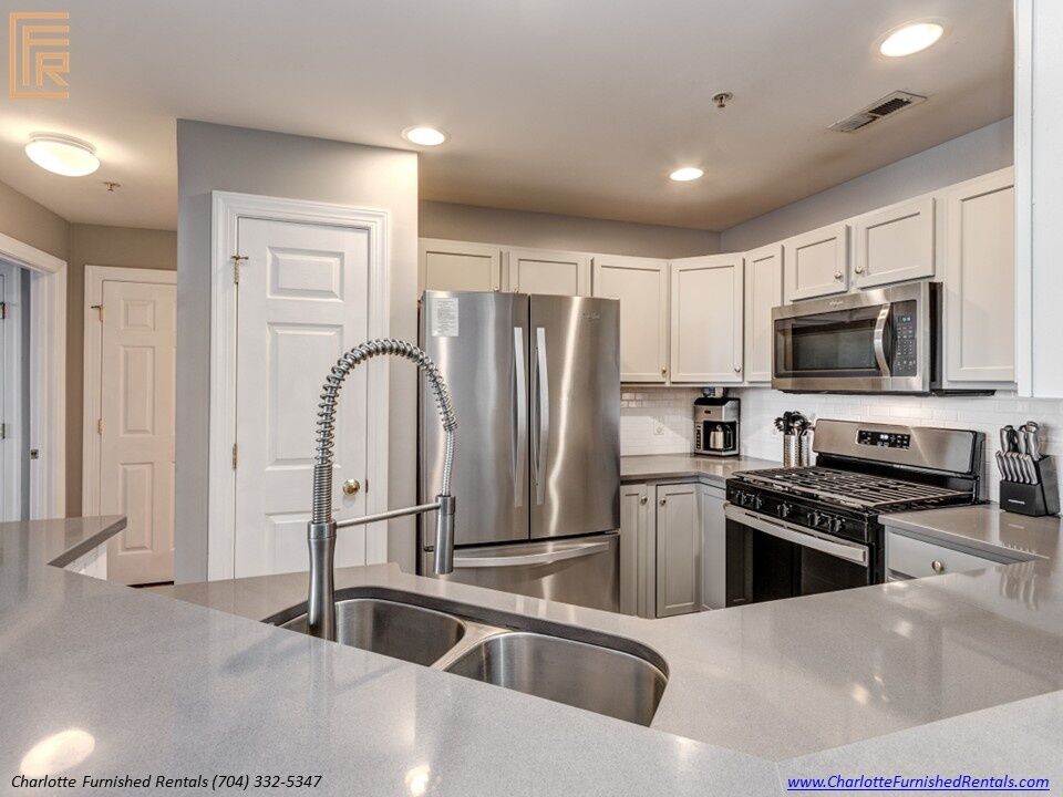 718-west-trade-unit-813-updated-kitchen-with-stainless-appliances-uptown-charlotte Kitchen breakfast bar opening to living room at 718 West Trade Street Unit 813, a furnished rental in Uptown Charlotte