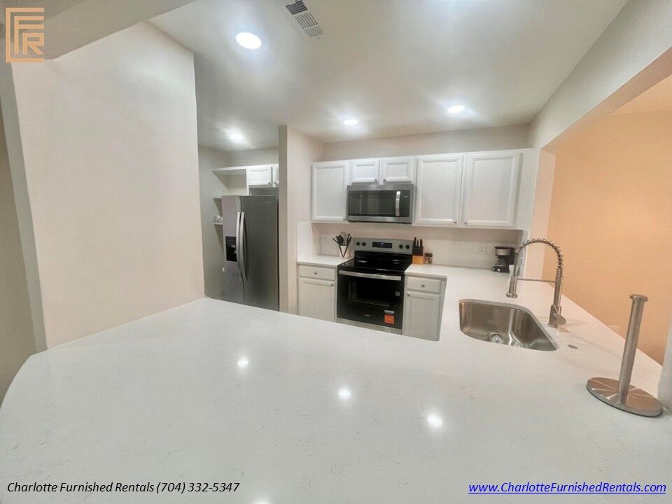 Renovated Kitchen with Quartz Countertops Fully equipped kitchen with quartz countertops, stainless steel appliances, recessed lighting and breakfast bar in furnished Charlotte rental.