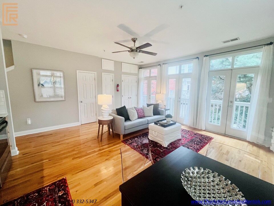 Slide5 Living Room Bright, professionally furnished living room with comfortable seating and natural light. Open-concept living area featuring modern furnishings and hardwood-style flooring. Comfortable living room with mounted television and adjoining dining area.