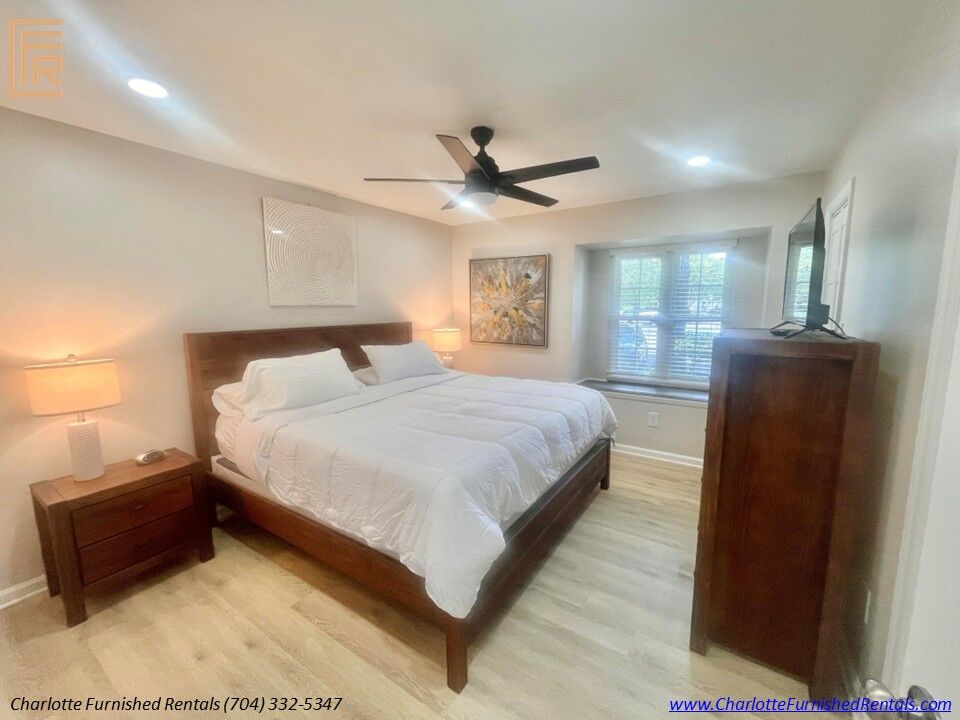 Primary Bedroom with King Bed Spacious primary bedroom featuring king bed, smart television, ceiling fan and large window in SouthPark furnished rental.