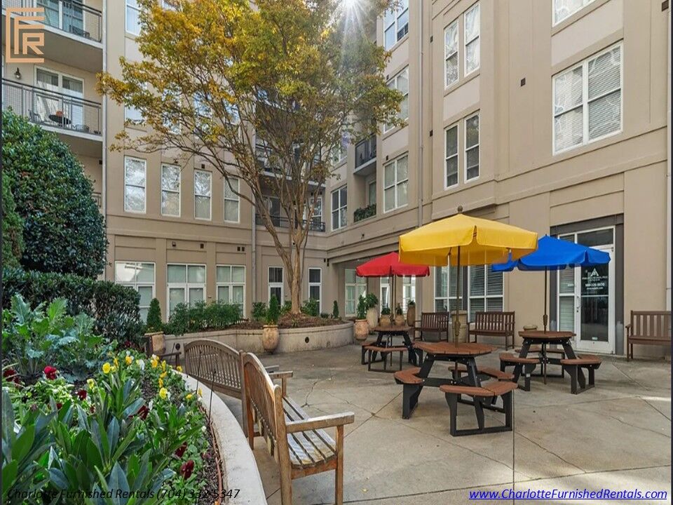 25-1315-east-blvd-courtyard-picnic-tables-charlotte Courtyard with picnic tables, colorful umbrellas, flowers, and benches at 1315 East Boulevard.